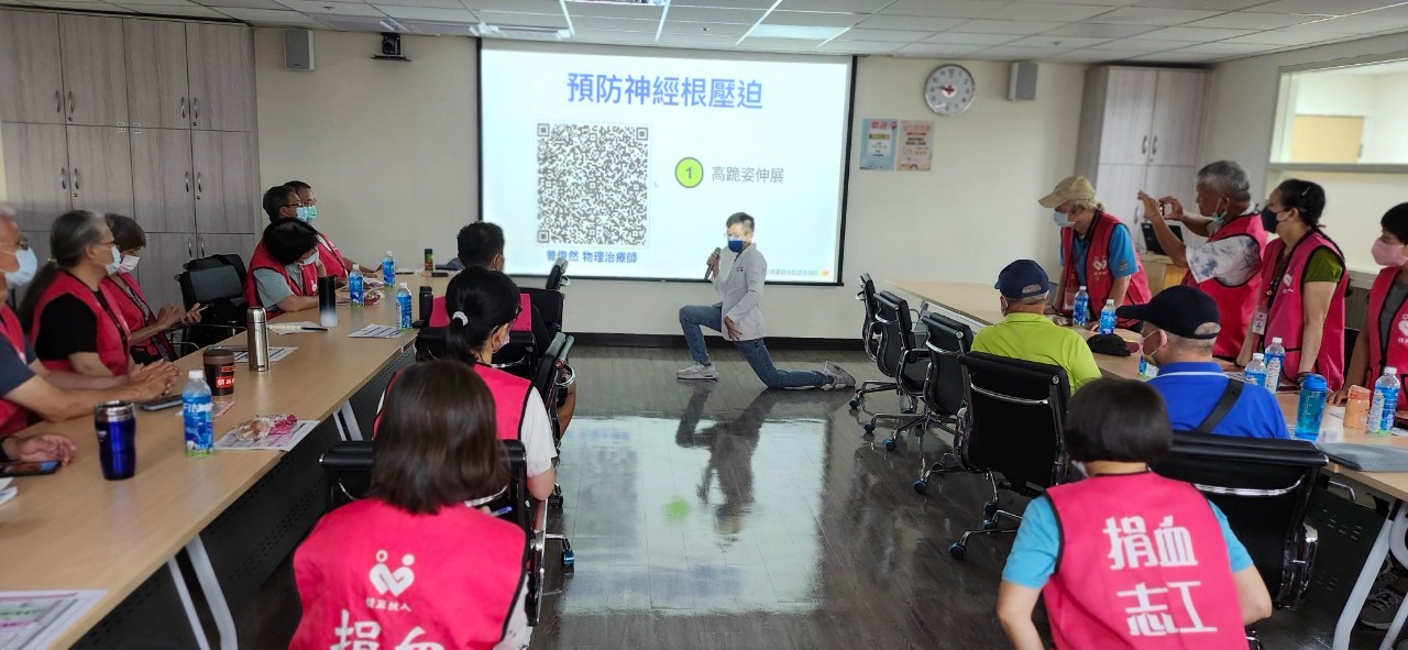 專業物理治療師現場示範「高跪姿伸展」運動，教導志工預防神經根壓迫及保護身體健康，現場氣氛熱絡，志工們專注學習，積極提升自我照護能力。